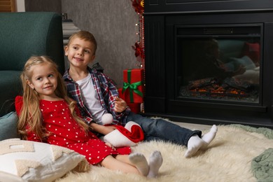 Cute children near fireplace at home. Christmas season