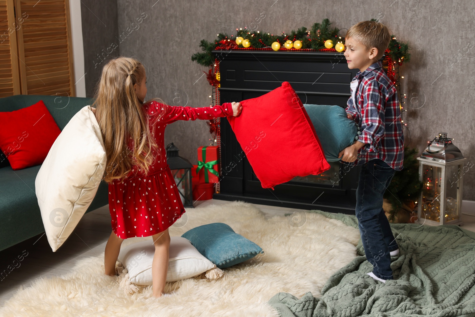 Photo of Little children having pillow fight at home. Christmas season