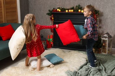 Photo of Little children having pillow fight at home. Christmas season