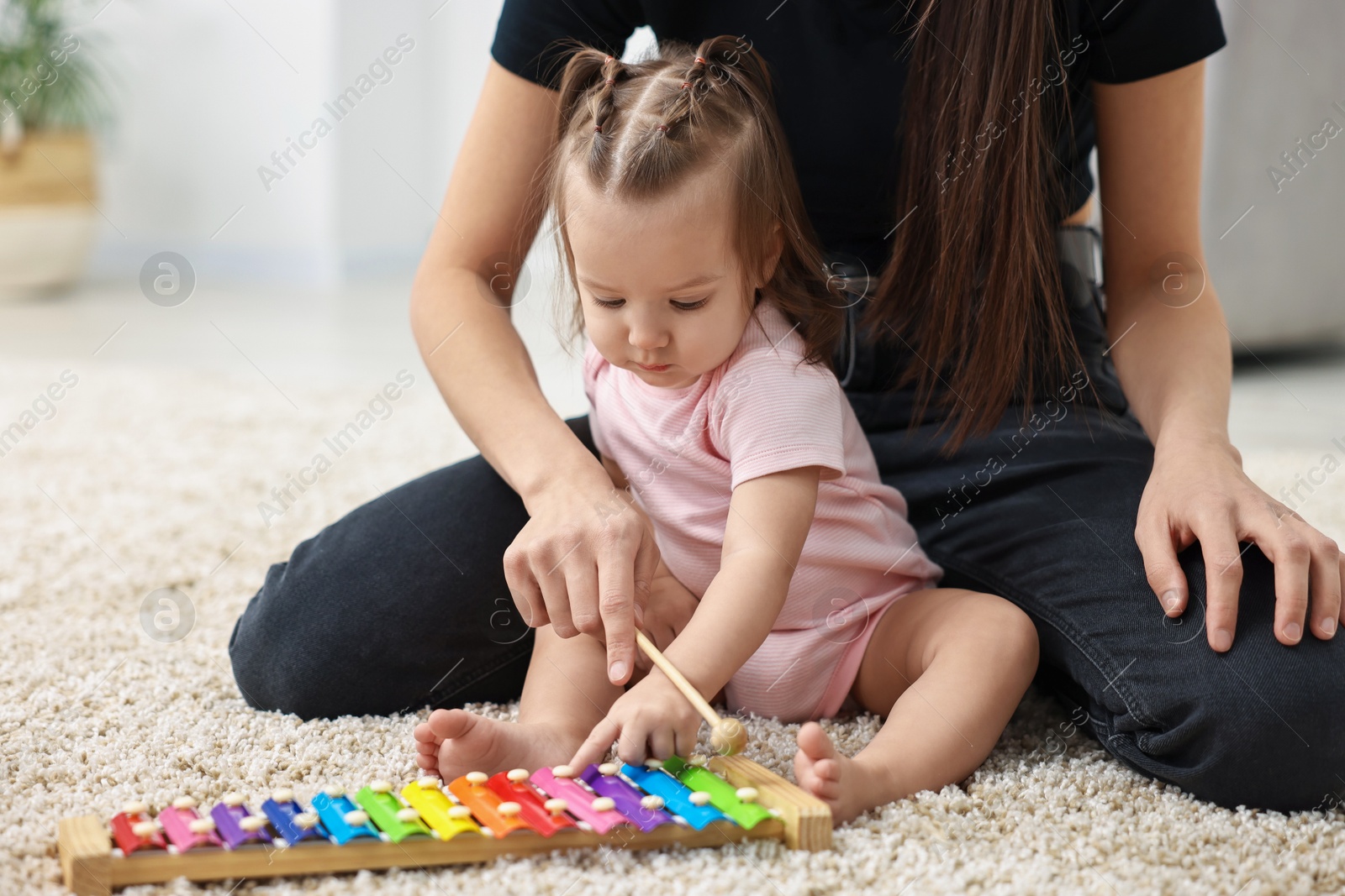 Photo of Mother and her baby playing with toy xylophone on floor at home