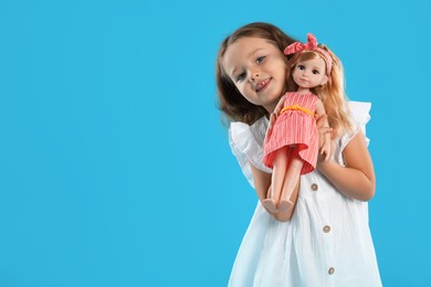 Photo of Cute little girl with doll on light blue background. Space for text