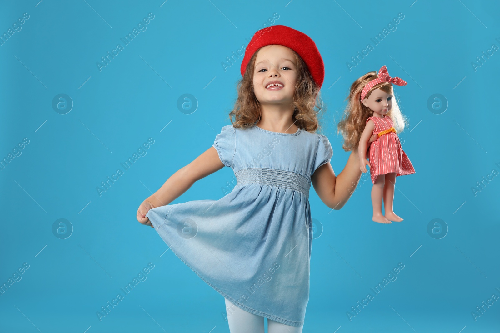 Photo of Cute little girl with doll on light blue background