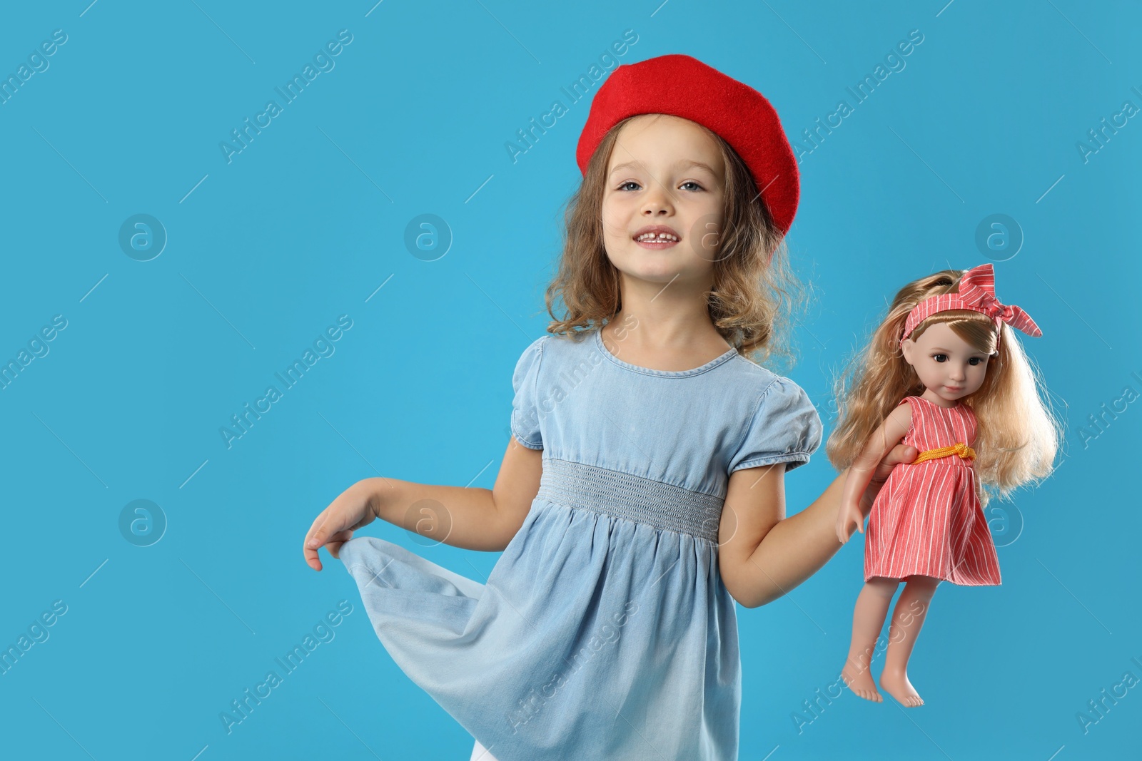 Photo of Cute little girl with doll on light blue background. Space for text