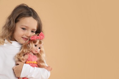 Photo of Cute little girl with doll on beige background. Space for text