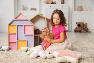 Photo of Cute little girl playing with her doll at home