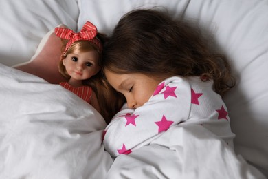 Photo of Little girl sleeping with doll in bed, top view