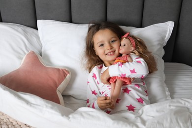 Photo of Cute little girl with doll in bed