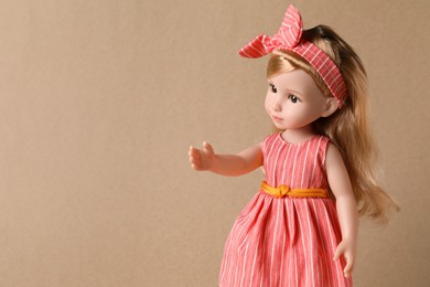 Photo of Beautiful doll in dress and headband on light brown background. Space for text