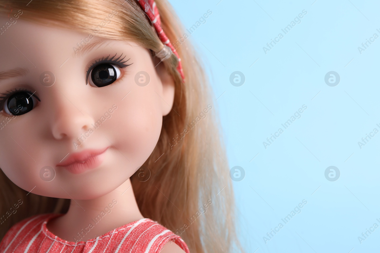 Photo of Beautiful doll on light blue background, closeup. Space for text