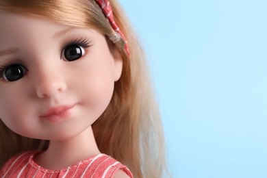 Photo of Beautiful doll on light blue background, closeup. Space for text