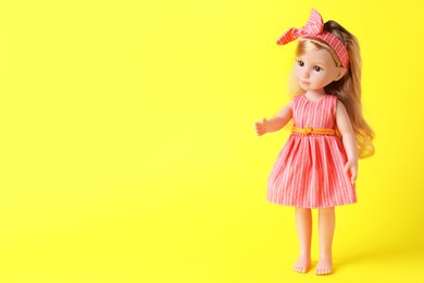 Beautiful doll in dress and headband on yellow background. Space for text