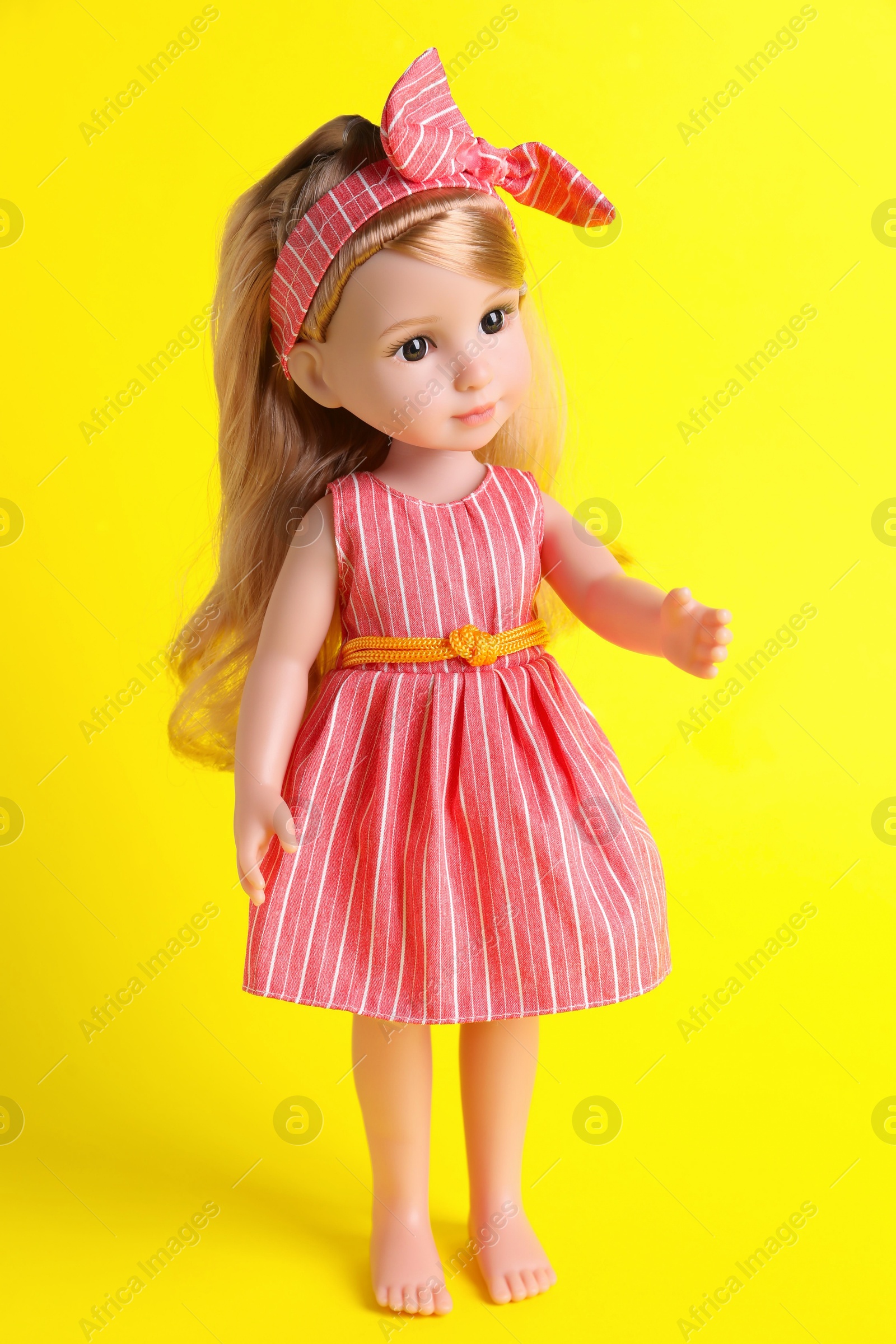 Photo of Beautiful doll in dress and headband on yellow background