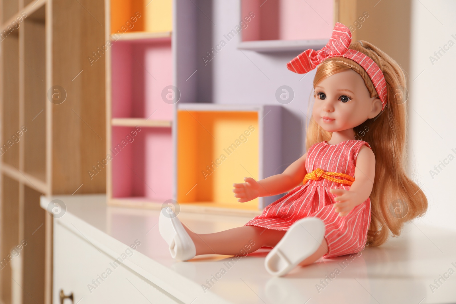 Photo of Beautiful doll in dress and headband on white table indoors, space for text