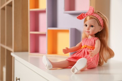 Beautiful doll in dress and headband on white table indoors, space for text