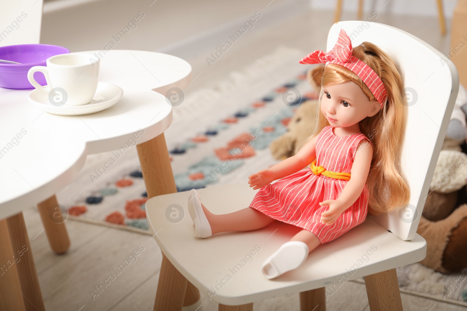 Photo of Beautiful doll in dress and headband on white chair indoors