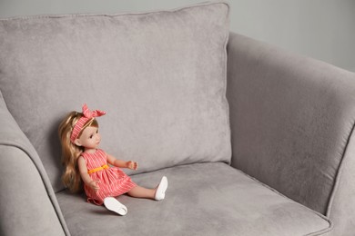 Photo of Beautiful doll with headband in armchair. Child's toy