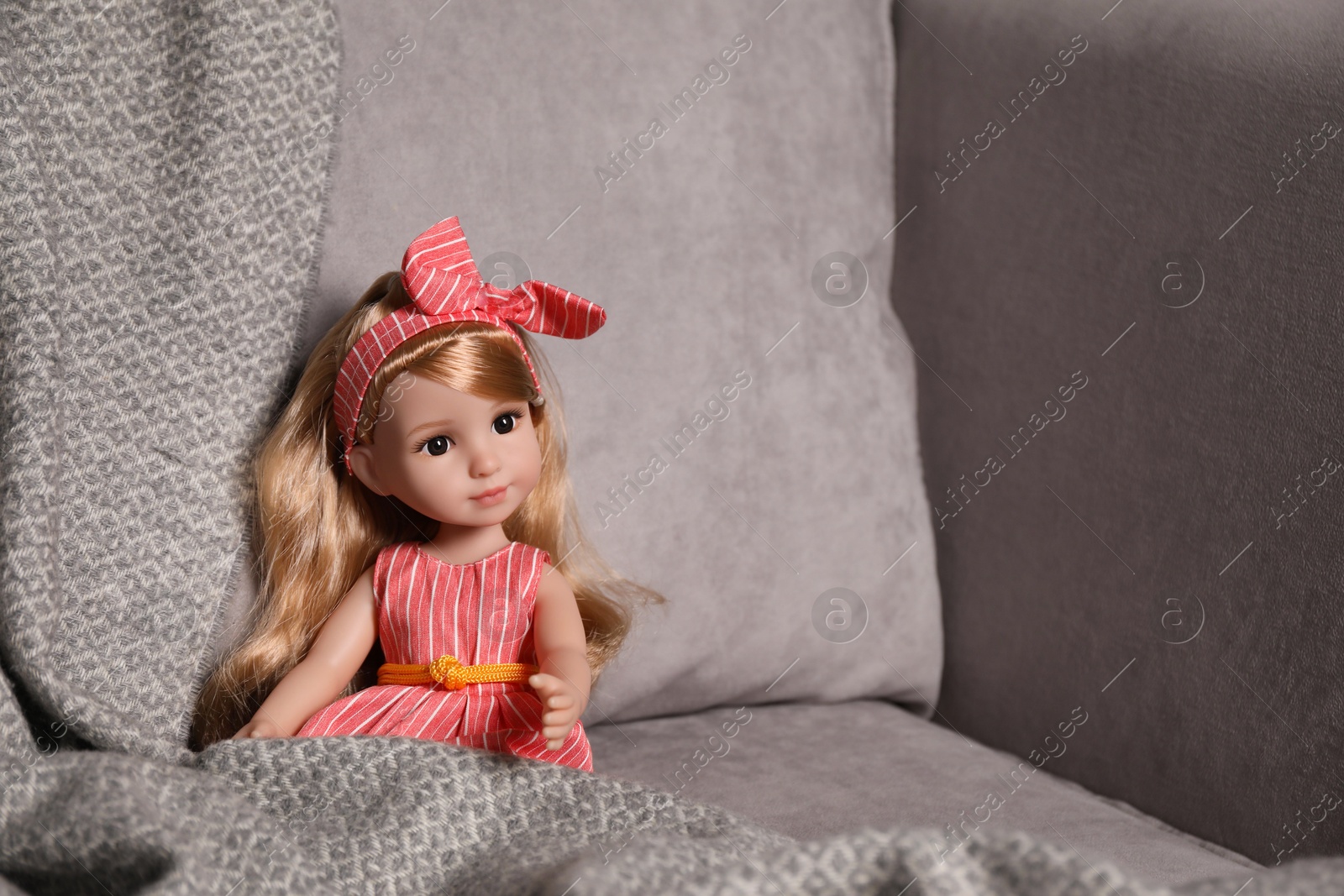 Photo of Beautiful doll and blanket in soft armchair. Space for text