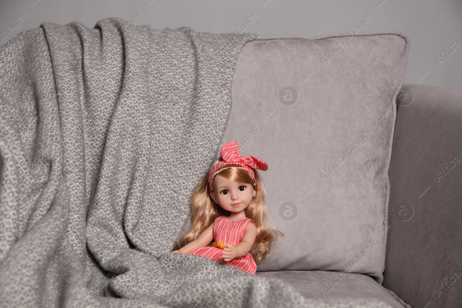 Photo of Beautiful doll and blanket in soft armchair