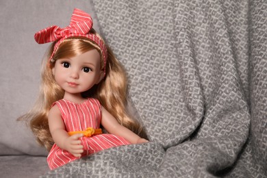 Photo of Beautiful doll and blanket in soft armchair