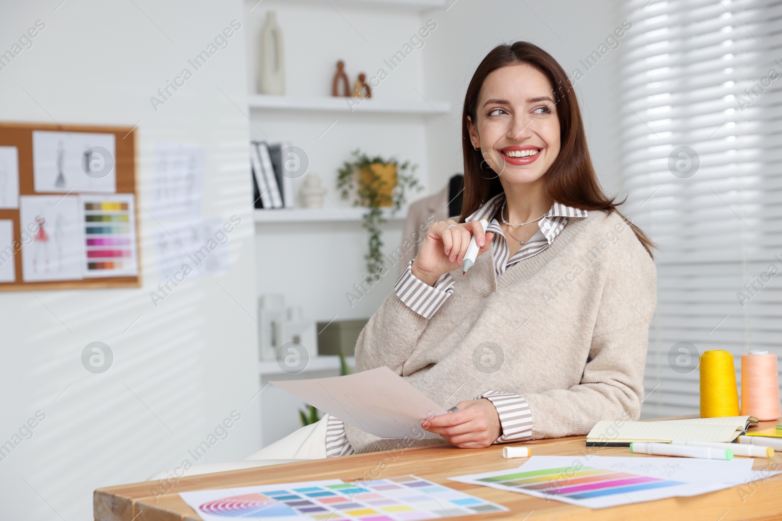 Photo of Fashion designer working at wooden table in workshop, space for text