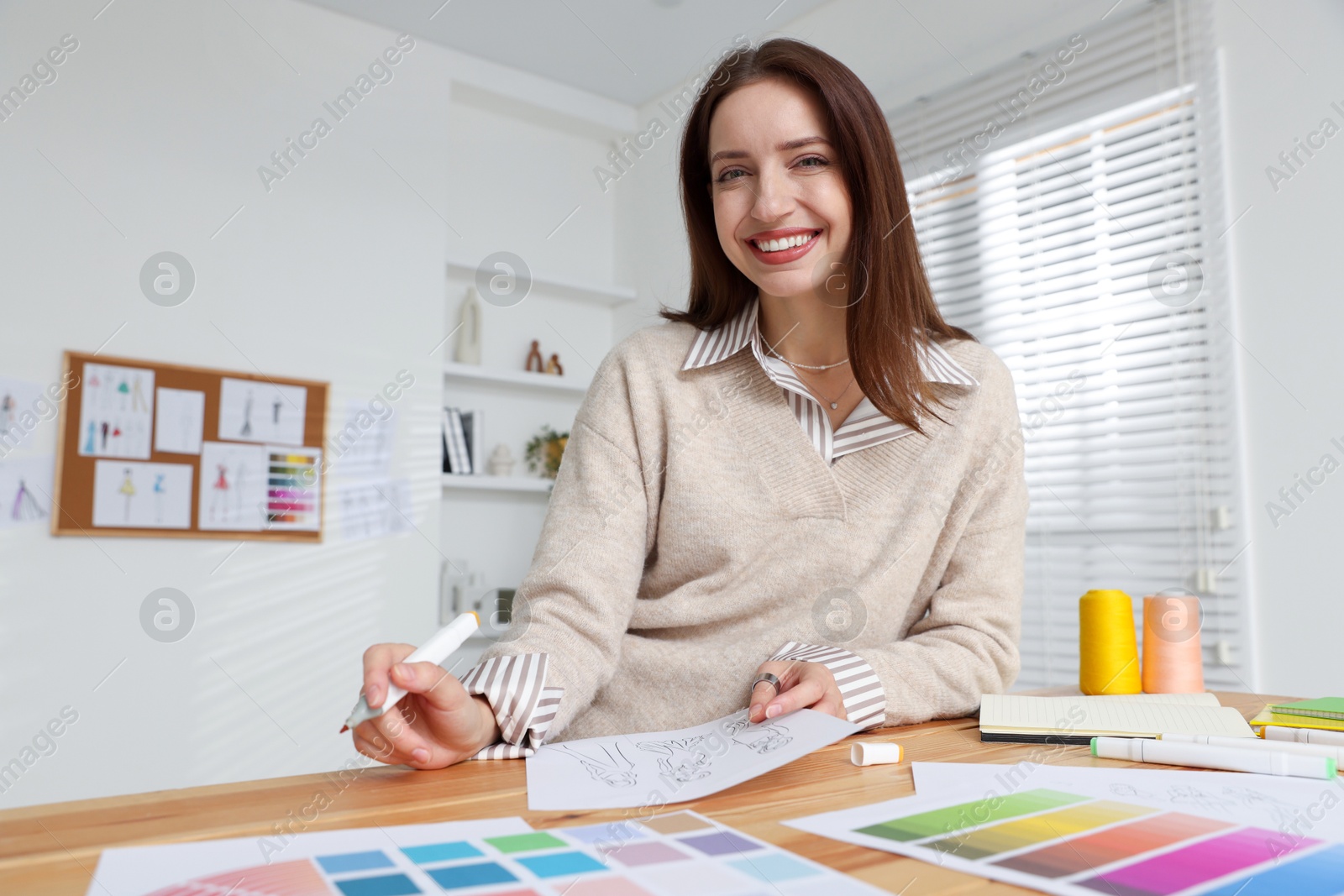 Photo of Fashion designer working at wooden table in workshop