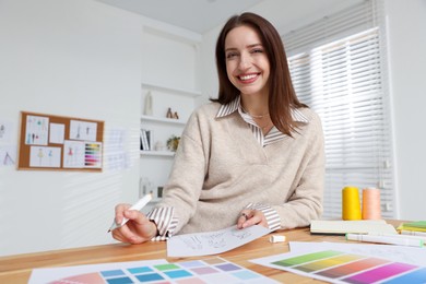 Photo of Fashion designer working at wooden table in workshop