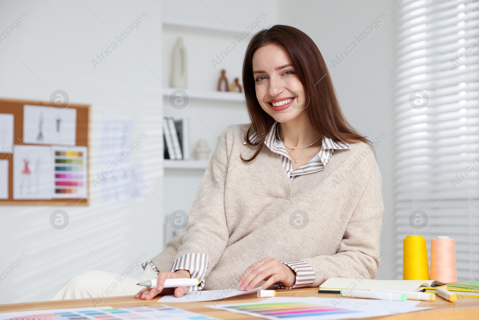 Photo of Fashion designer working at wooden table in workshop