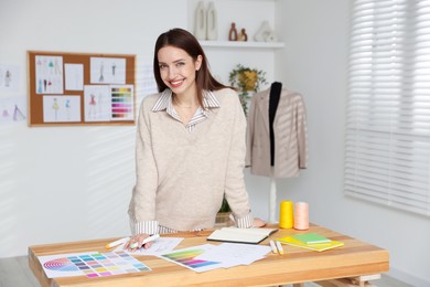 Fashion designer working at wooden table in workshop