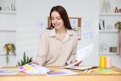 Fashion designer working at wooden table in workshop