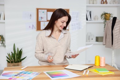 Fashion designer working at wooden table in workshop