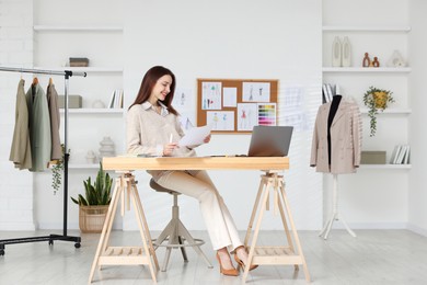 Fashion designer working at wooden table in workshop