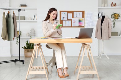 Photo of Fashion designer working at wooden table in workshop