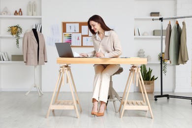 Photo of Fashion designer working at wooden table in workshop