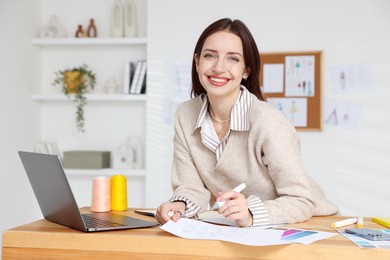 Photo of Fashion designer working at wooden table in workshop