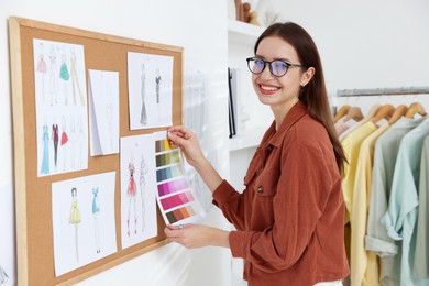 Photo of Fashion designer pinning color palette to corkboard in workshop