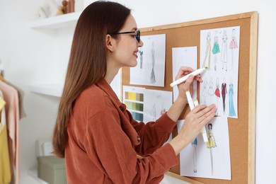 Photo of Fashion designer drawing sketch of clothes in workshop