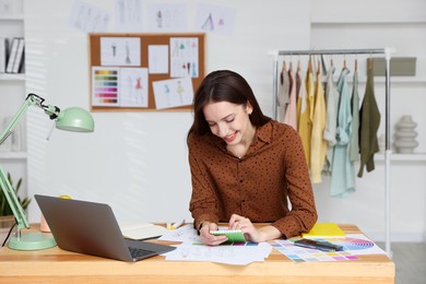 Photo of Fashion designer working at wooden table in workshop