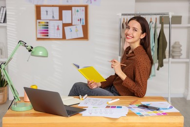 Fashion designer working at wooden table in workshop