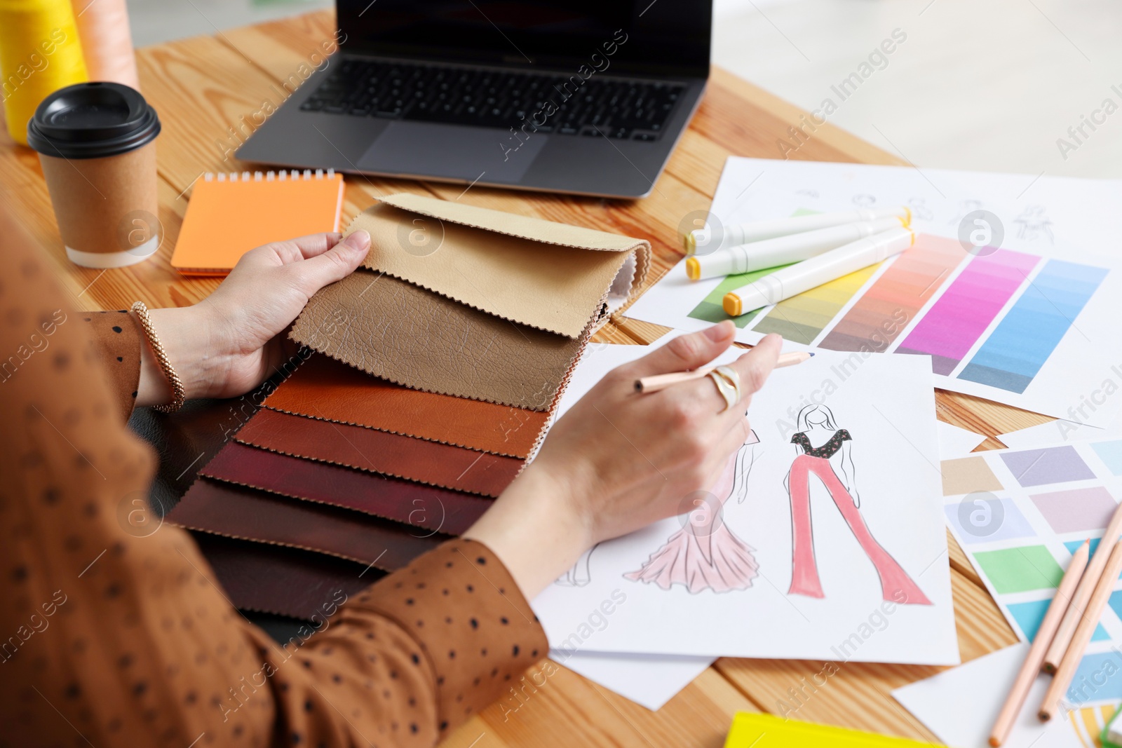 Photo of Fashion designer choosing fabric among colorful samples at wooden table in workshop, closeup