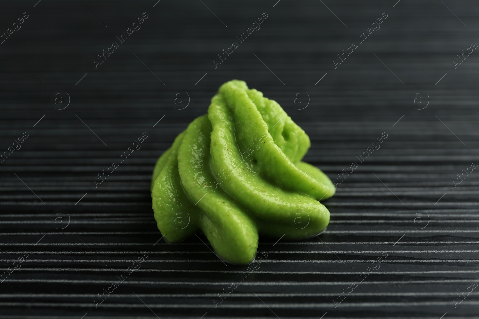 Photo of Hot wasabi paste on black textured table, closeup