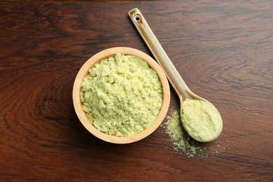 Photo of Dry wasabi powder in bowl and spoon on wooden table, top view