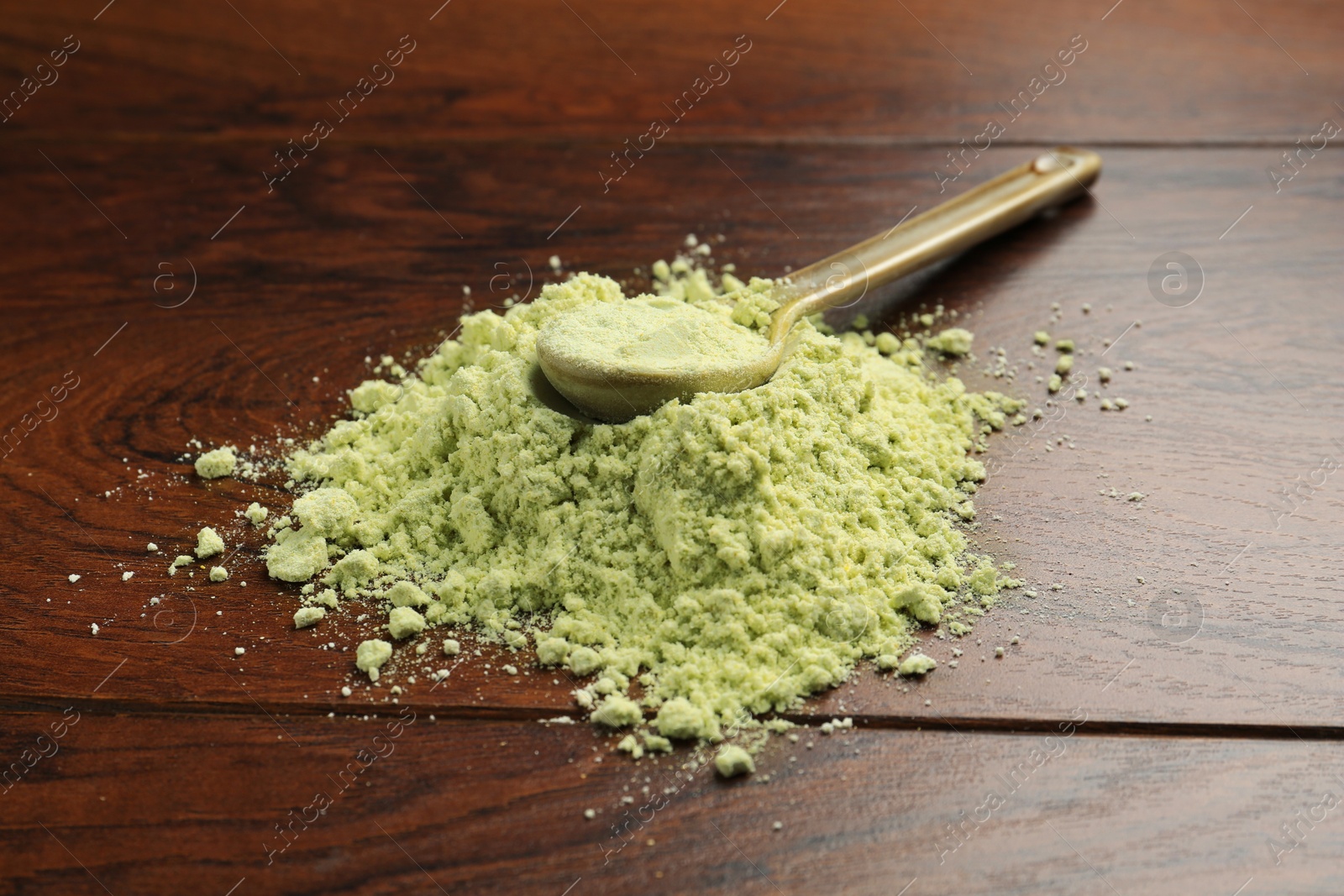 Photo of Pile of dry wasabi powder and spoon on wooden table, closeup