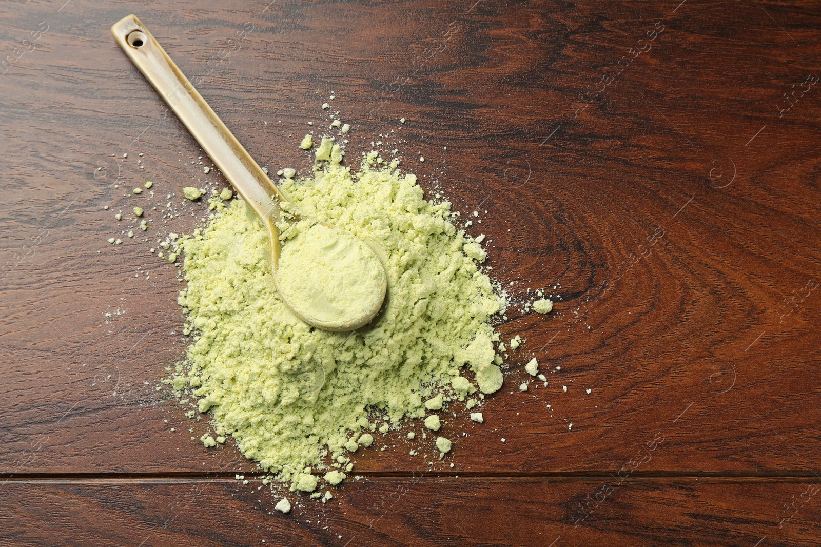 Photo of Pile of dry wasabi powder and spoon on wooden table, top view. Space for text