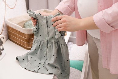 Photo of Woman with baby clothes at home, closeup