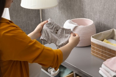 Photo of Pregnant woman with baby clothes at home, closeup