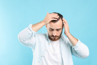 Photo of Baldness problem. Man with receding hairline on light blue background