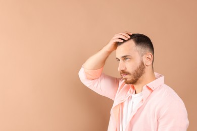 Photo of Baldness problem. Man with receding hairline on beige background, space for text