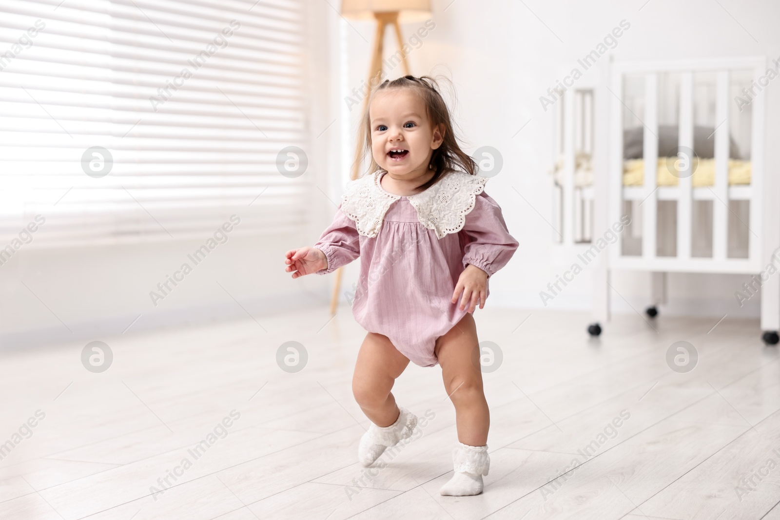 Photo of First steps. Cute little baby learning to walk at home