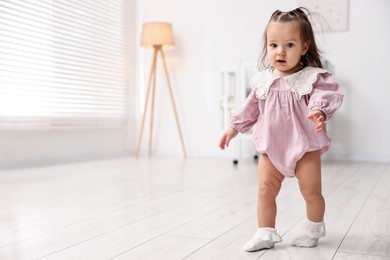 Photo of First steps. Cute little baby learning to walk at home, space for text