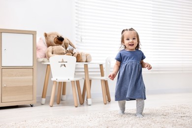 Photo of First steps. Cute little baby learning to walk at home